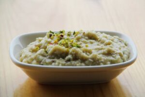 A close-up of creamy Kheer with a garnish of chopped nuts and saffron strands.