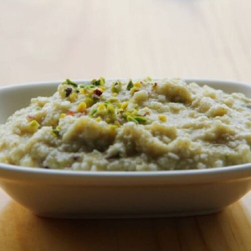 A close-up of creamy Kheer with a garnish of chopped nuts and saffron strands.