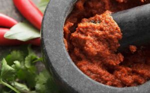 Vibrant red curry paste in a wooden bowl.